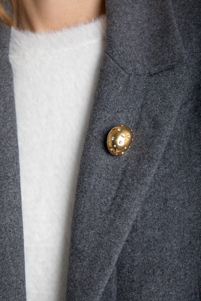 

Золотиста брошка овальної форми зі стразами